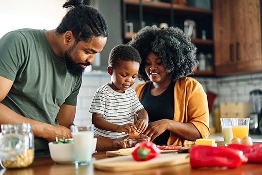 An african-american family makes a healthy meal together in the kitchen