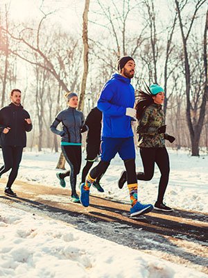 a group of runners run on a snowy wooded trail